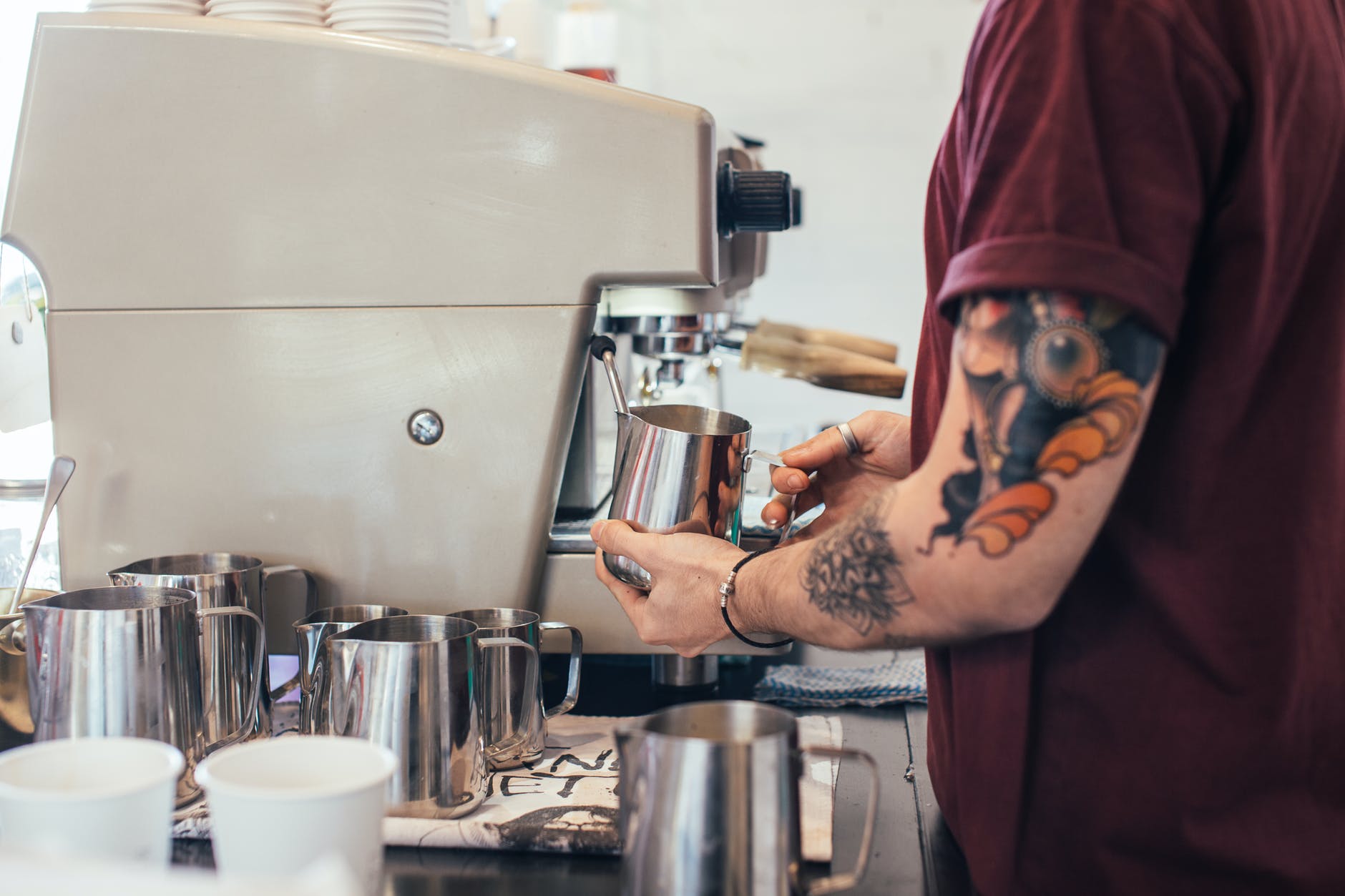 tattooed barista making coffee with coffee machine
